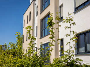 modern-residential-building-exterior-with-green-foliage-clear-blue-sky