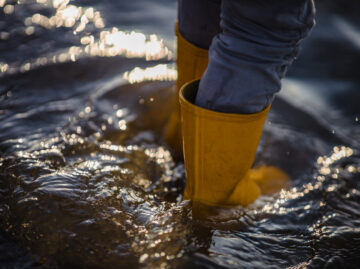 person in blue denim jeans and yellow boots standing on water